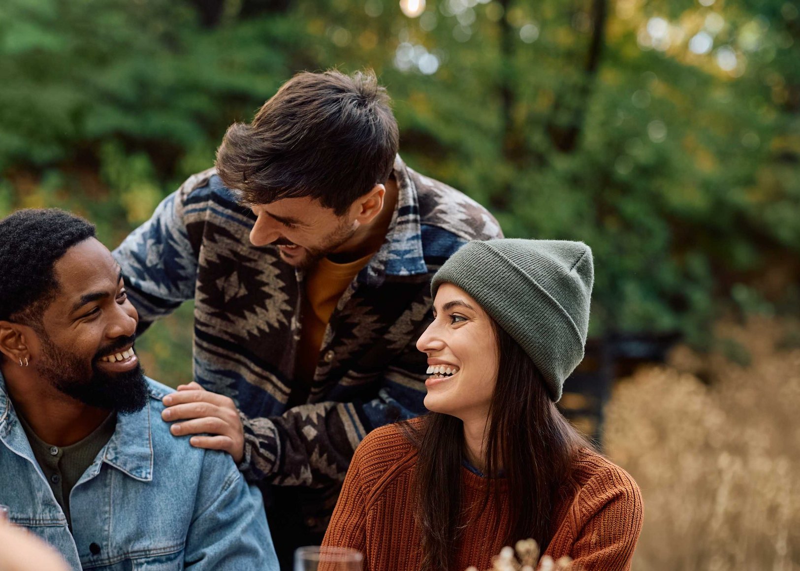 Friends laughing together around an outdoor dinner table